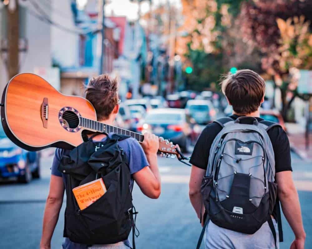 Can Backpackers Save the World? History and Benefits of Backpacking 3 Two backpackers backpacking with a guitar