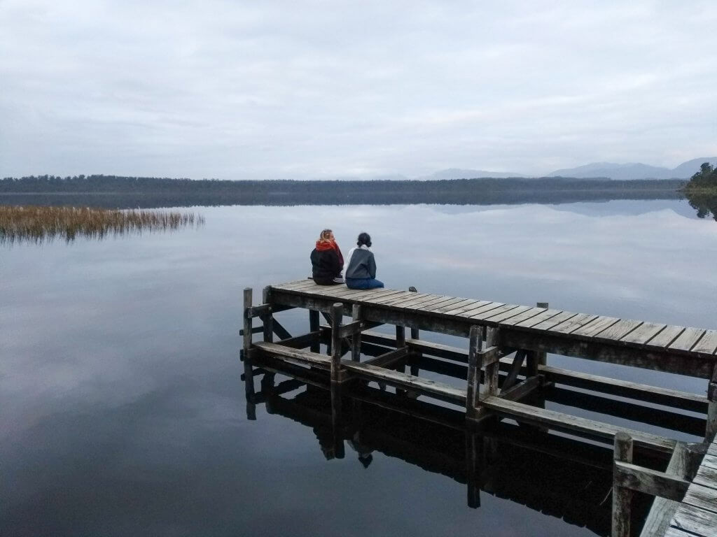 two girls sitting on a jetty