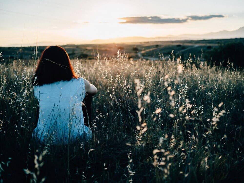 Woman sitting in a field at golden hour