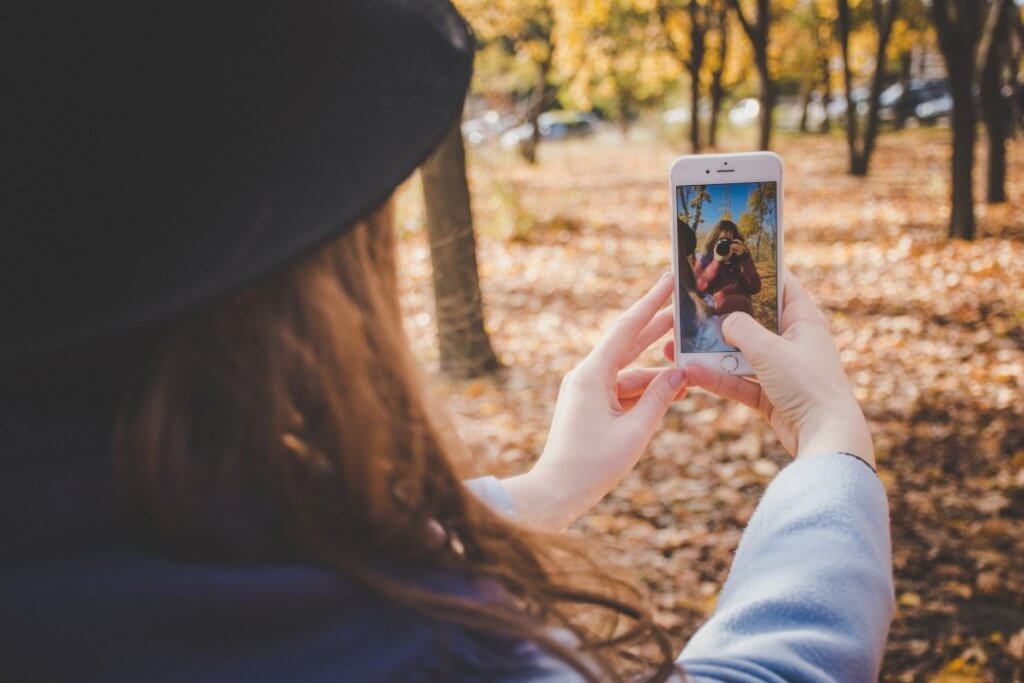 10 Best Free Travel Apps to Download Before Your Next Trip 7 A girl taking a photo with her phone camera