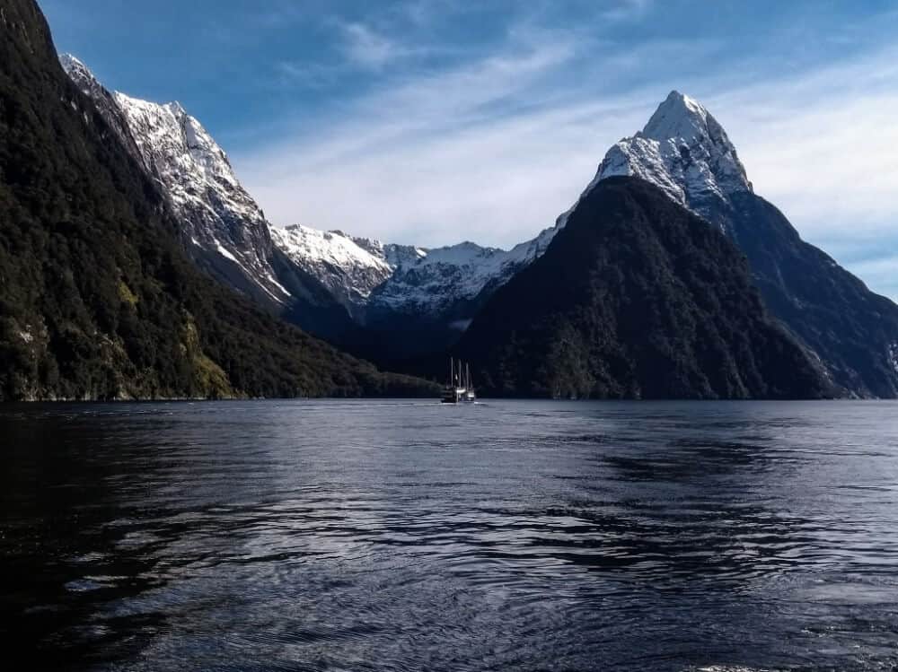Milford Sound in winter - the cruise boat on the water with snow-capped mountains behind. 