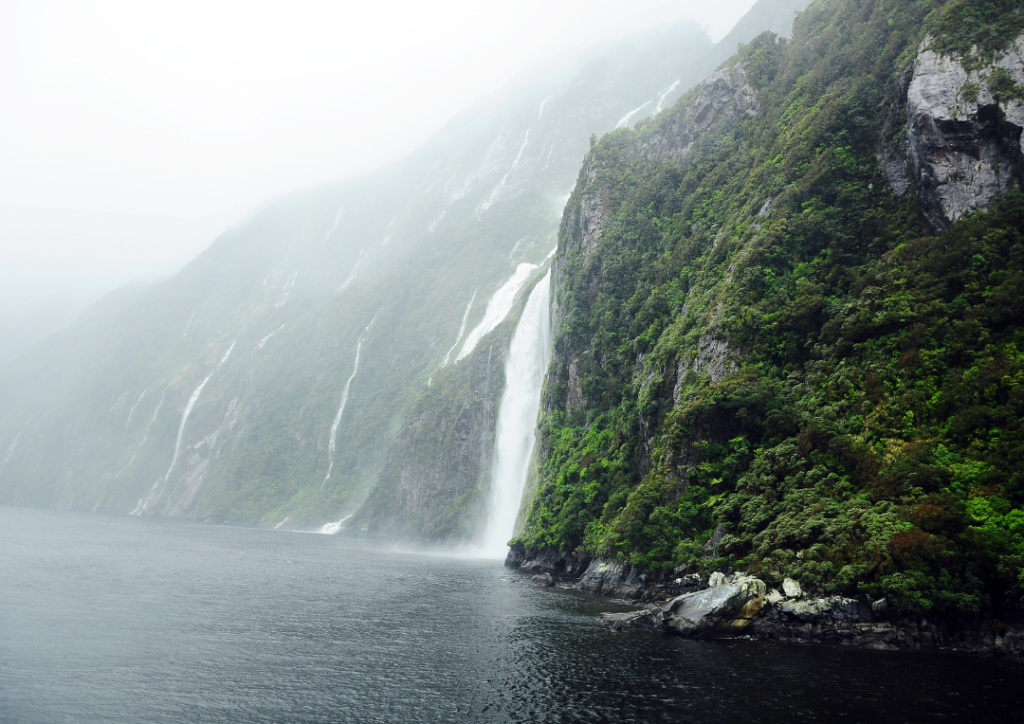 Waterfalls cascading down mountains at Milford Sound in a mist.