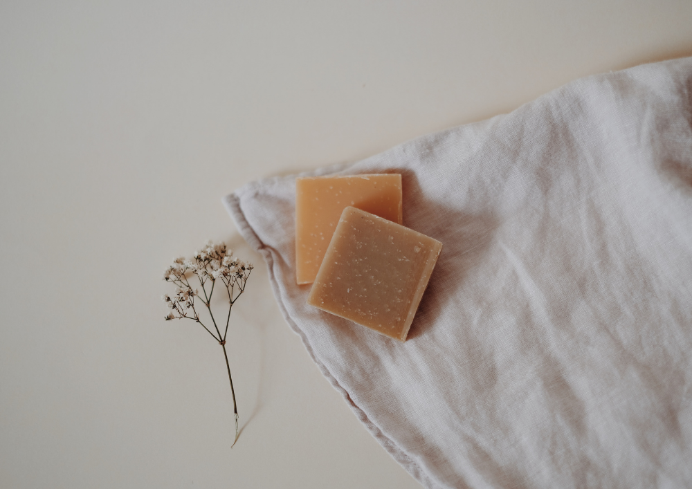 Two orange solid shampoo bars on a white muslin cloth. 