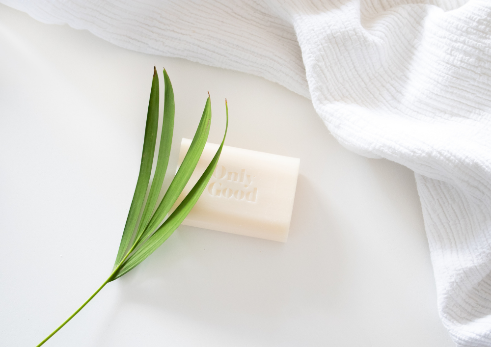 A solid soap bar on a white background with a green leaf.