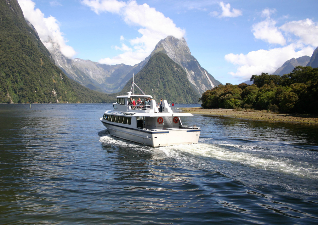 Boat on the water with mountains behind on a sunny day at Milford Sound. 
