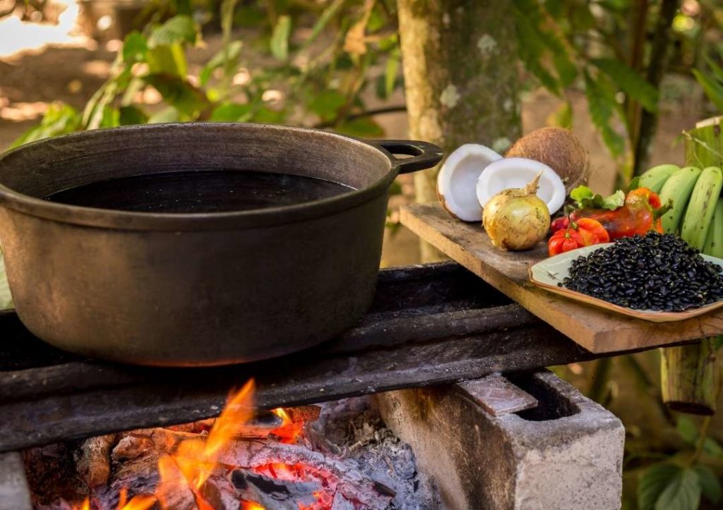A pot of food being prepared over a fire. 