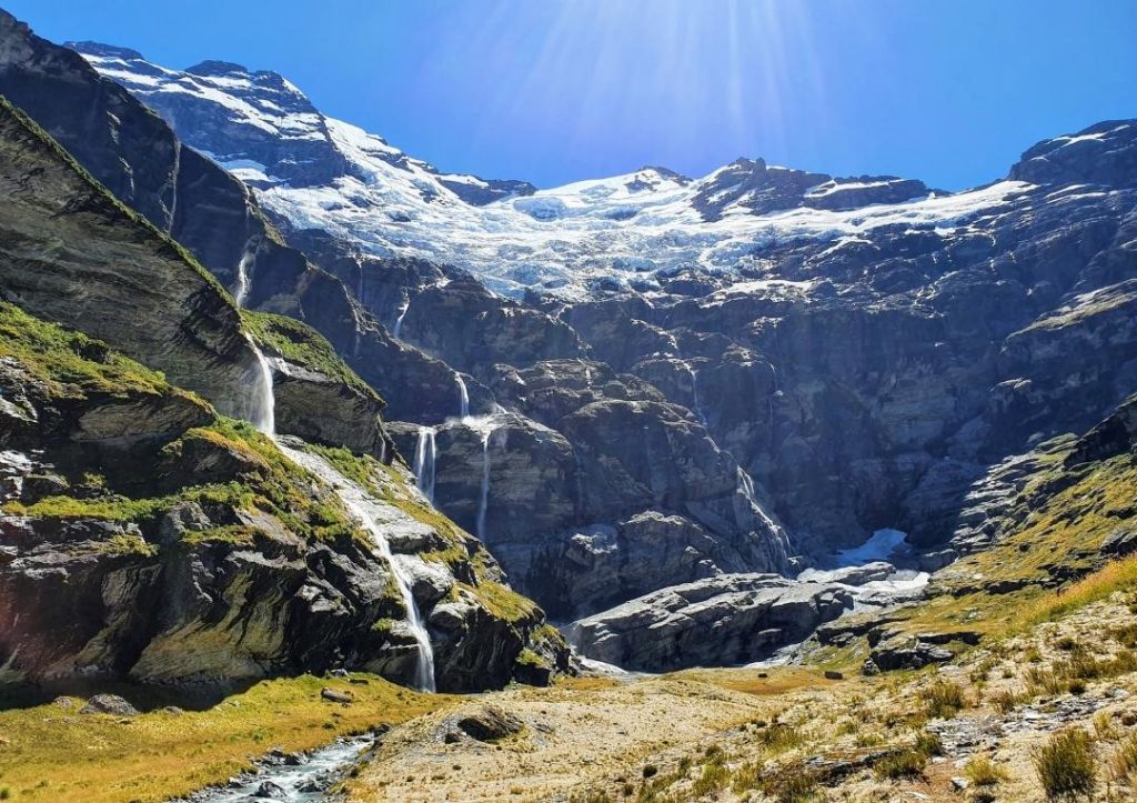 14 Incredible Hikes On the South Island of New Zealand 14 Mountains and a stream on the path on the Earnslaw Track, one of the best hikes on the South Island of New Zealand.