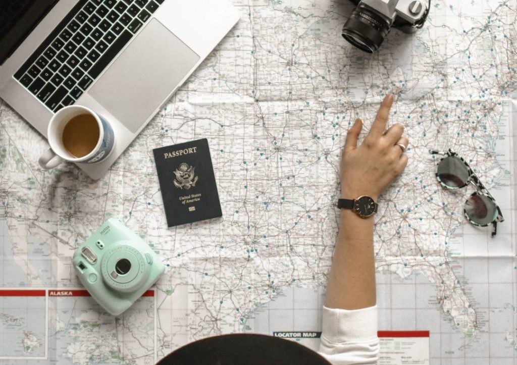 Person pointing at a map with a laptop for how to travel solo. 