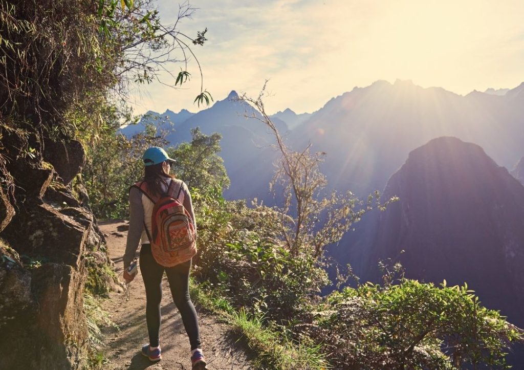 Woman with a backpack hiking along a [ath through the mountains. 