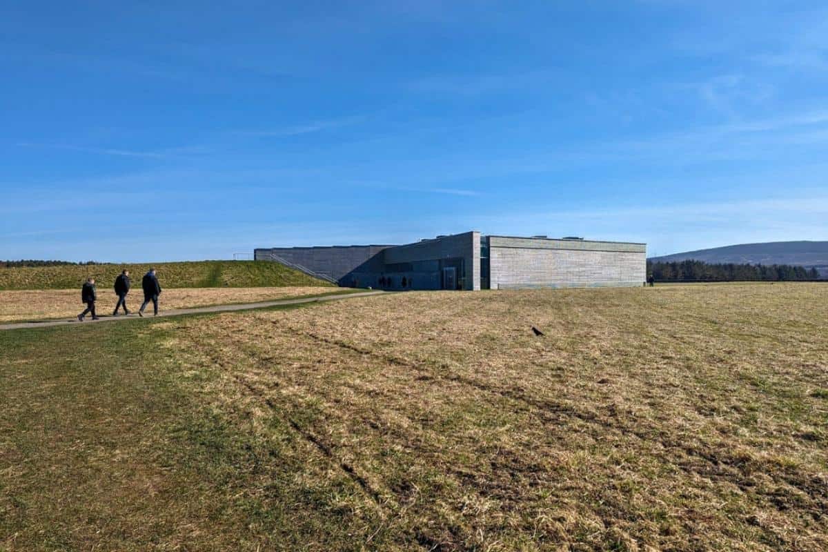Best 10-day Scottish Highlands itinerary (No Car Needed!) 7 A modern, angular visitor center blends into a wide open field under a clear sky, located at the historic Culloden Battlefield.