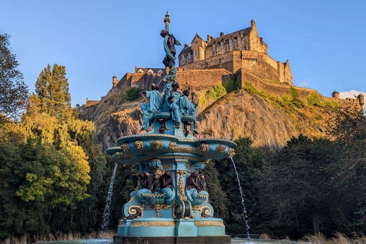 Best 10-day Scottish Highlands itinerary (No Car Needed!) 21 The ornate Ross Fountain stands in the foreground with Edinburgh Castle dramatically perched on a rocky hill behind it, basking in golden light.
