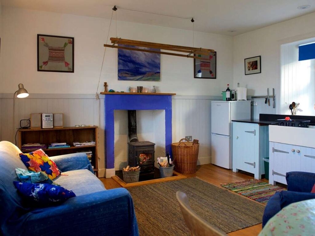 The interior of Haunn Cottage. A lounge with sofas and a wood-burning fireplace. A snug cottage. 