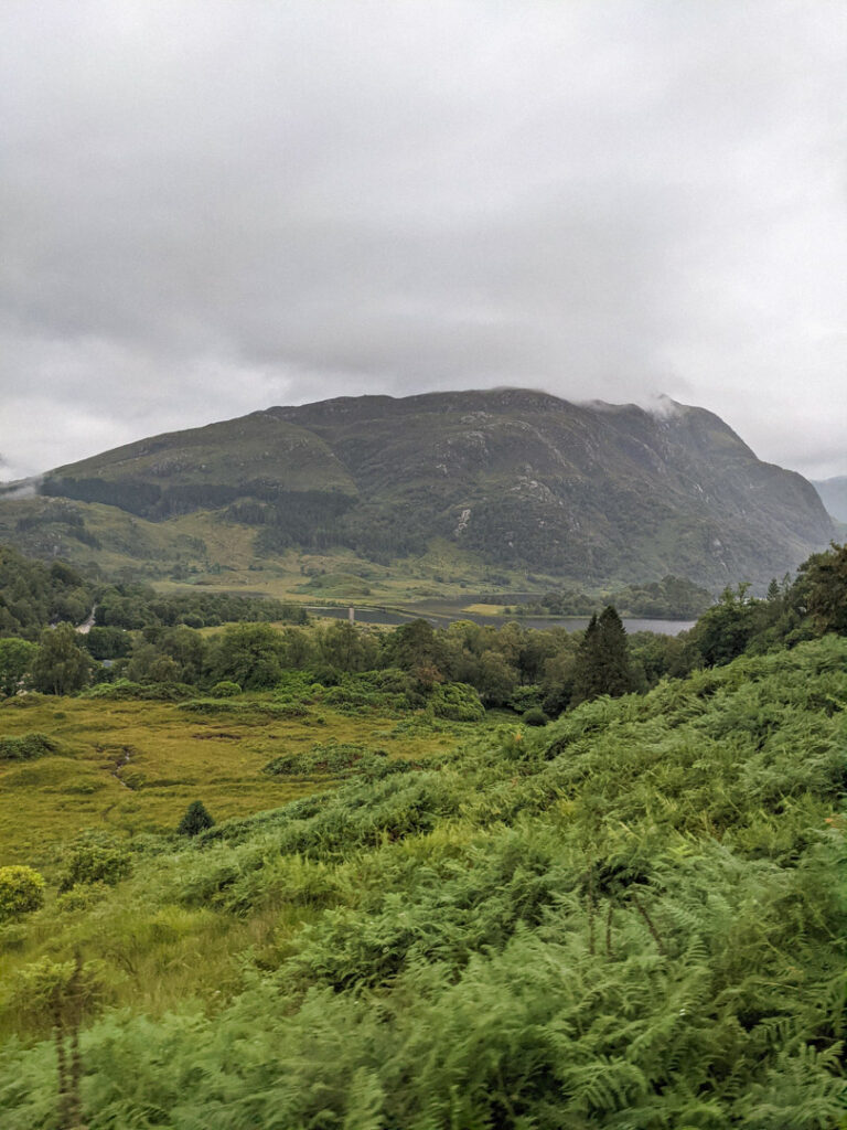 View of Glenfinnan Monument with green hills in the background. 