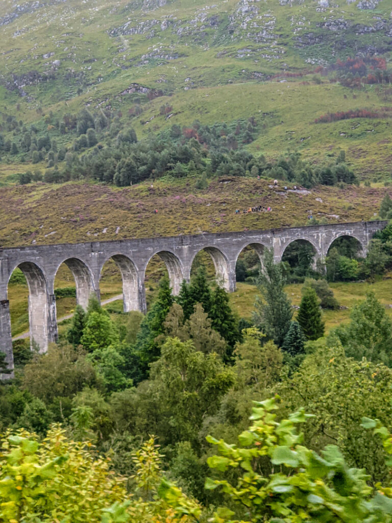 Glenfinnan Viaduct with people on the hill in the background for this Jacobite steam train review. 