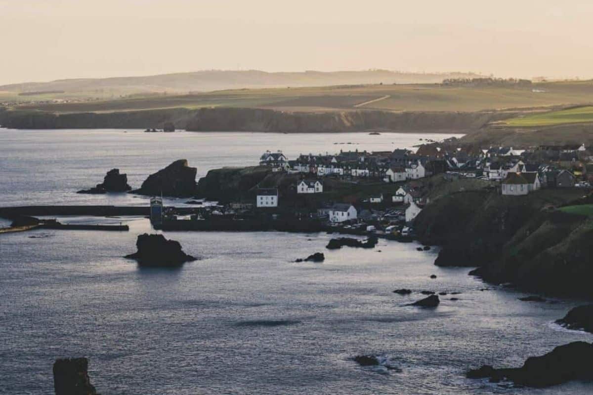 The village of St Abbs at sunset with cliffs in the background. One of the best day trips from Edinburgh by train or bus. 