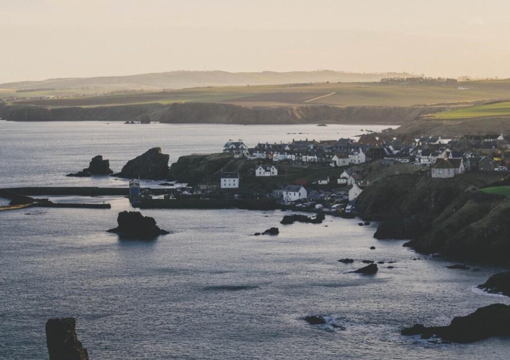 The village of St Abbs at sunset with cliffs in the background. One of the best day trips from Edinburgh by train or bus. 