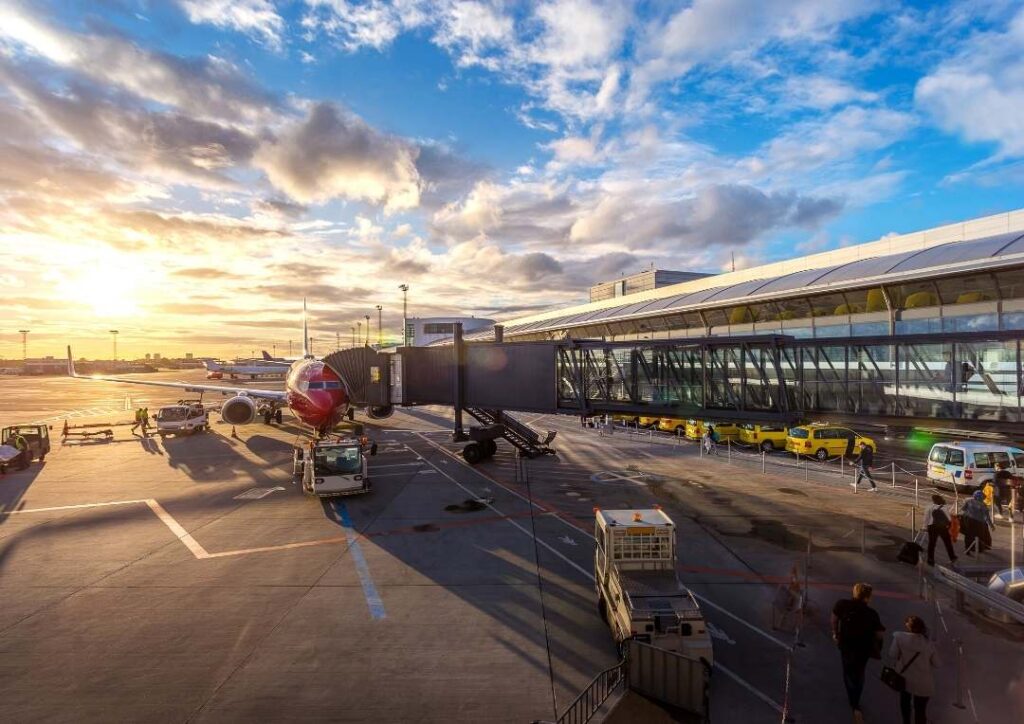 An aeroplane at an airport with the sunset behind it. 