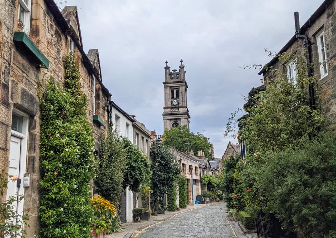 A cobblestone street in Edinburgh with a church behind. 