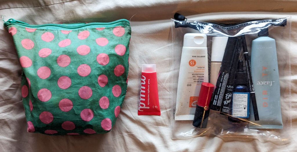 Pink deodorant tube next to a pink spotted wash bag and a clear travel bag for nuud deodorant review. 