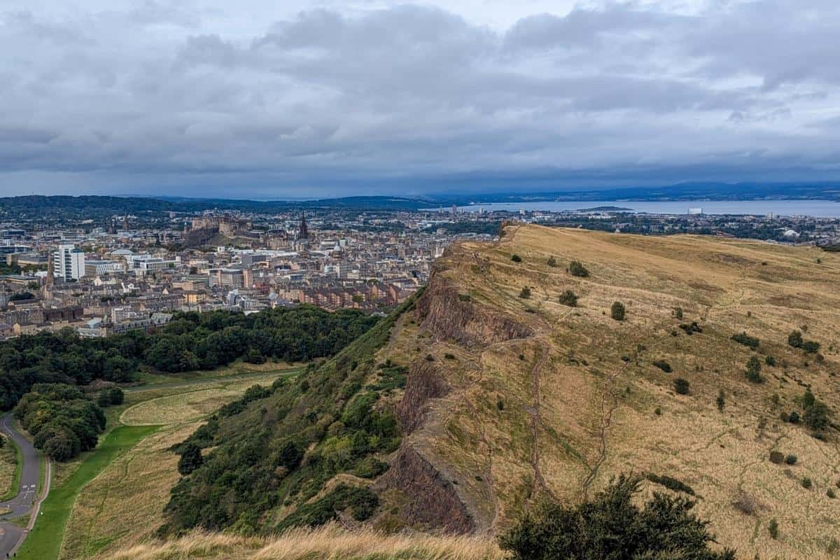 View of the jagged Salisbury Crags from above near the summit of Arthur's Seat. Edinburgh is in the background. 