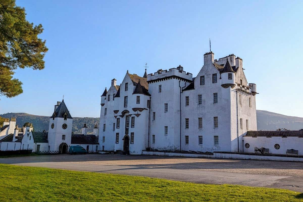 13 Best Places to Visit in Scotland by Train 9 The white facade of Blair Castle on a sunny day, with its towers and turrets standing out against a bright blue sky.