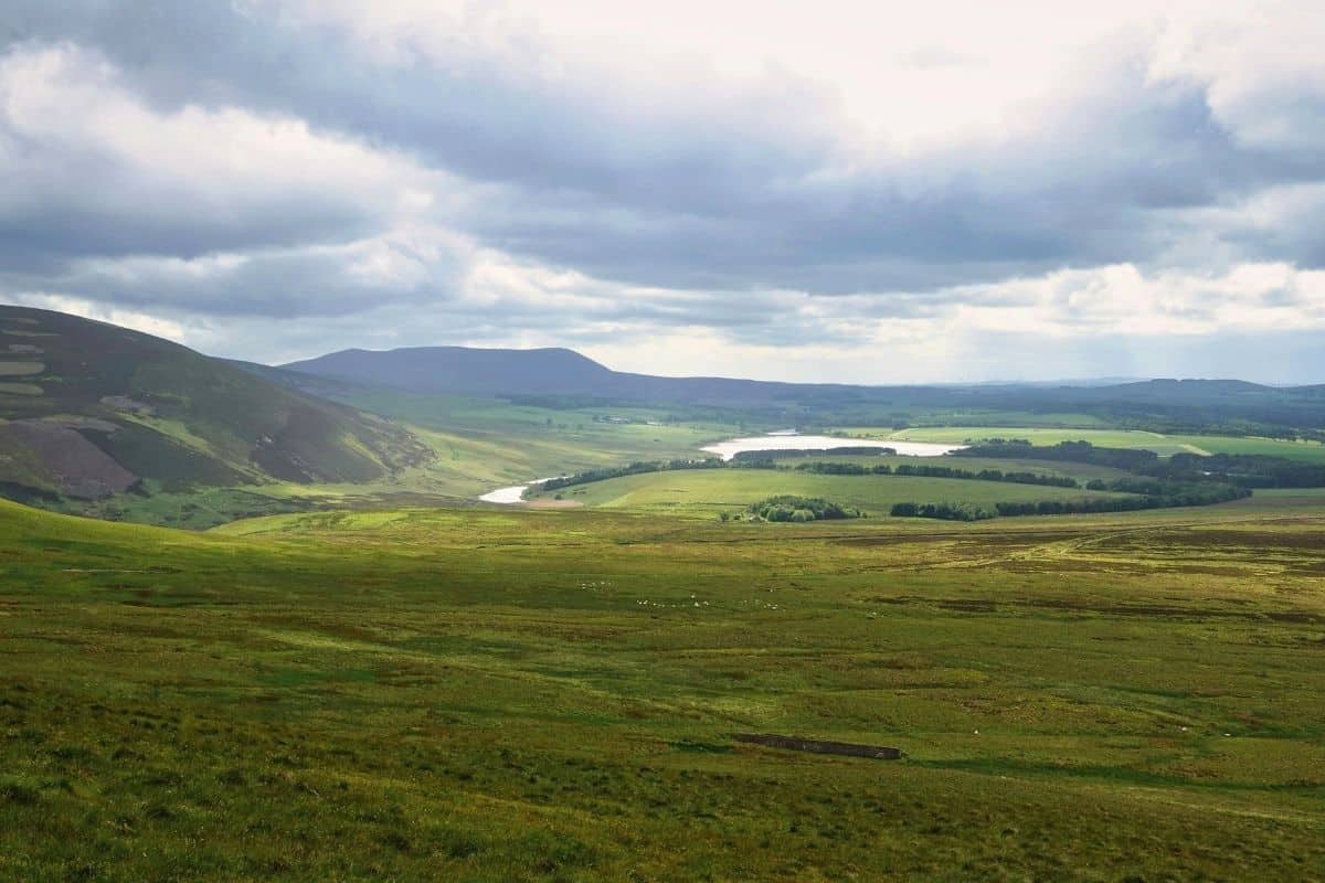7 Most Scenic Train Journeys in Scotland with Epic Views 10 Green Pentland Hills with bright but grey clouds above and trees in the distance.
