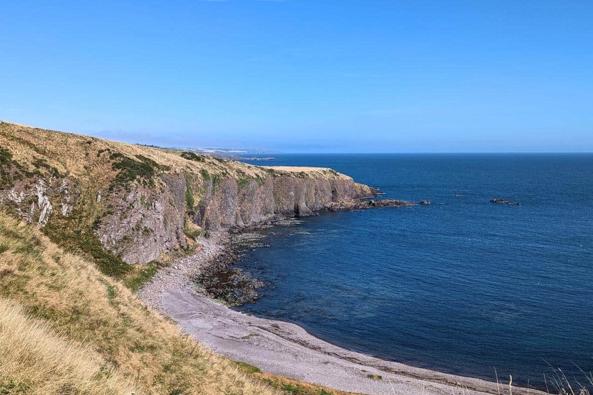 7 Most Scenic Train Journeys in Scotland with Epic Views 7 View of the North Sea on a very clear day with a acloudless blue sky above. There is a white shingle beach in the foreground. Stonehaven on the east coast of Scotland.