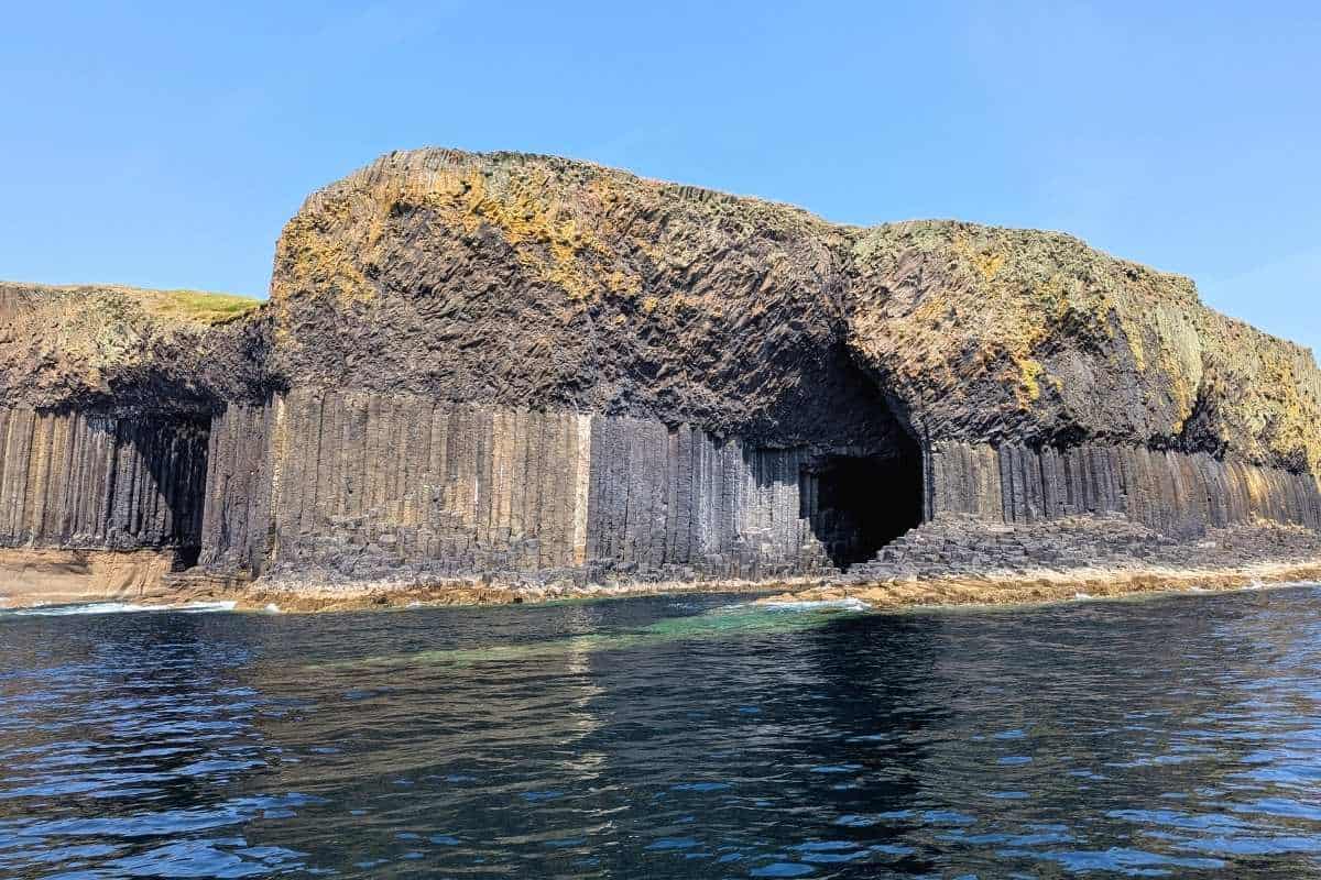 A sea cave made from basalt rock columns and with a yellow / greyish tint. This is Fingal's Cave on a tour with Staffa Tours, one of the best things to do in Oban. 