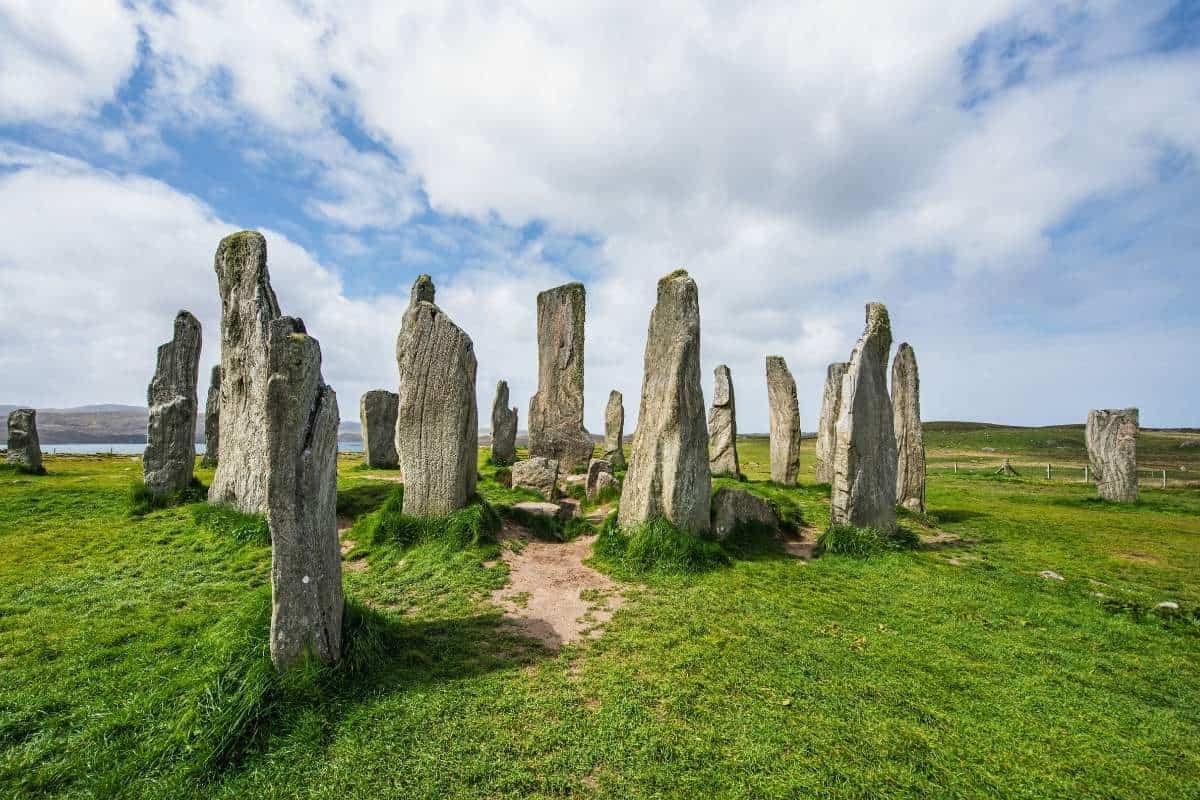 A ring of standing stones rise up from bright green grass. The Calanais Standing Stones on the Isle of Lewis. 