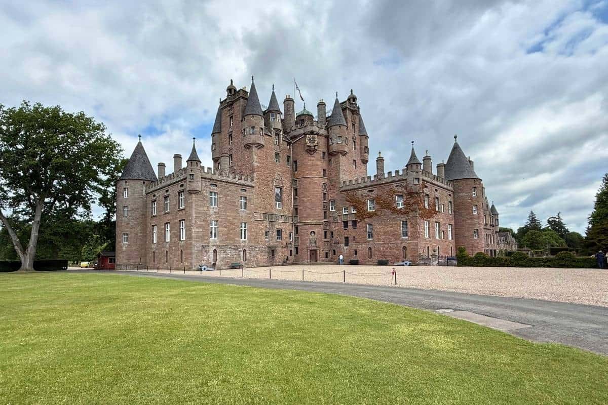 A large castle with towers and a clock tower with a big gravel drive in front. Glamis Castle in Angus. 