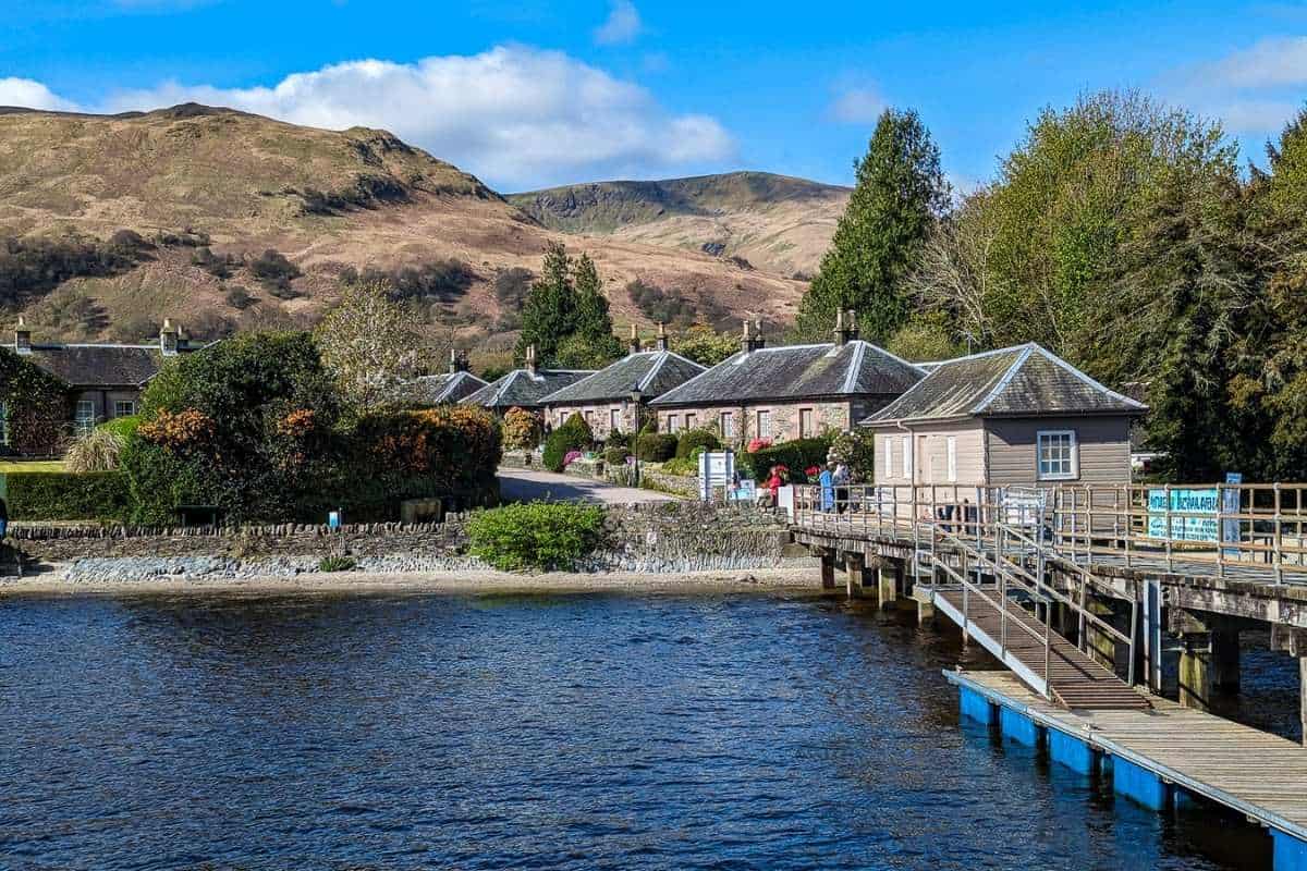 A pretty village with slate-roofed cottages line a loch with rugged hills behind.  Luss on LOch Lomond. 