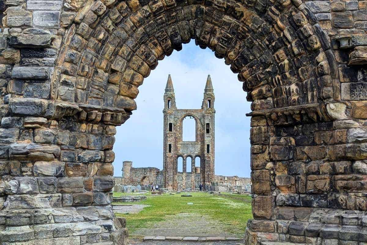 A ruined abbey tower framed by a stone archway. St Andrews Cathedral in Fife, one of the loveliest regions in Scotland. 
