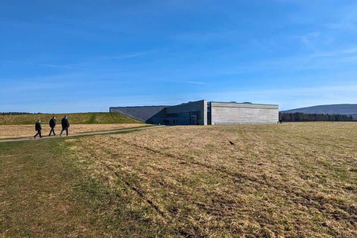 10 Easy Day Trips from Inverness Without a Car 2 Culloden Battlefield with the low structure of the visitor centre. Three people are walking up to it.