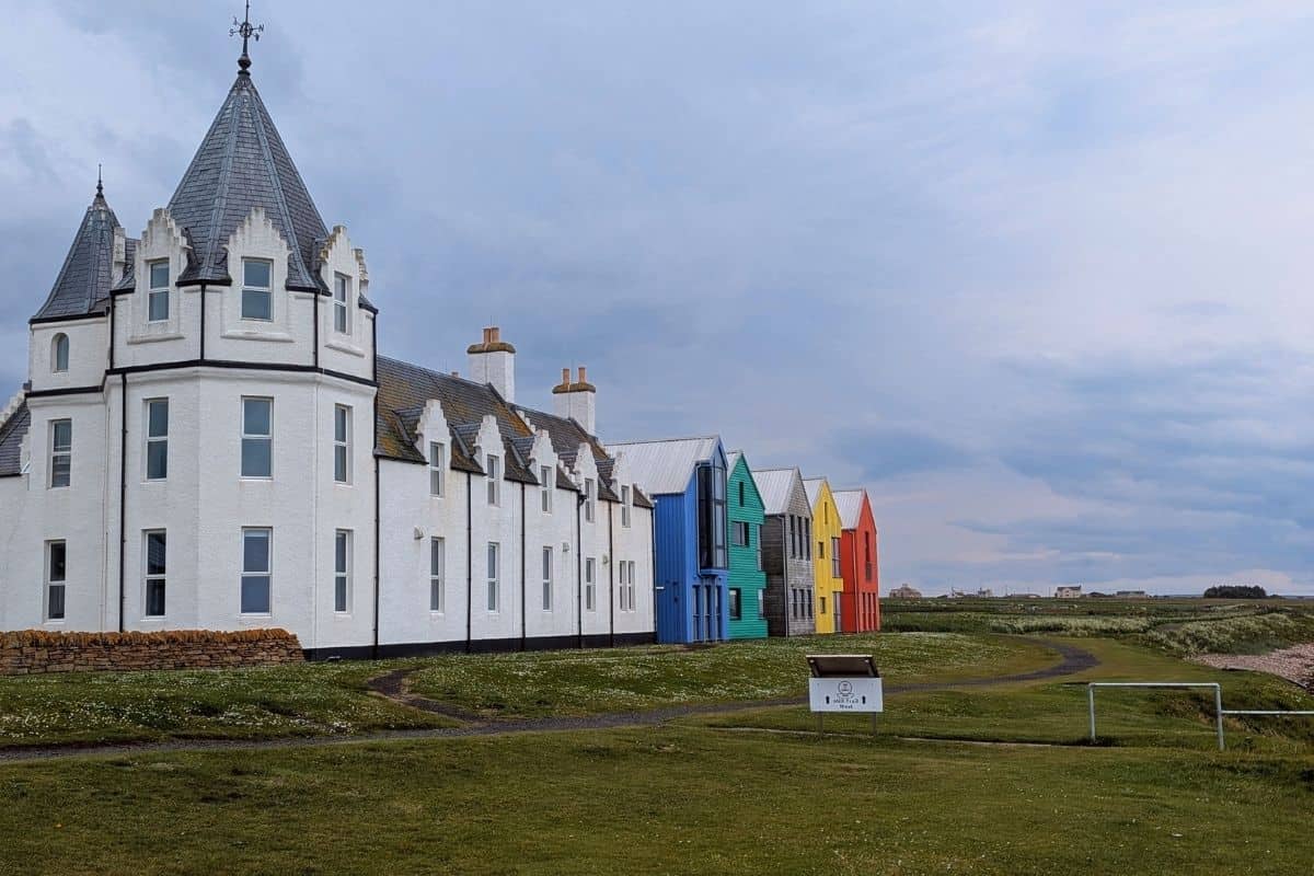 10 Easy Day Trips from Inverness Without a Car 17 A white building next to five colourful houses on a flat grassy ground at John O'Groats.
