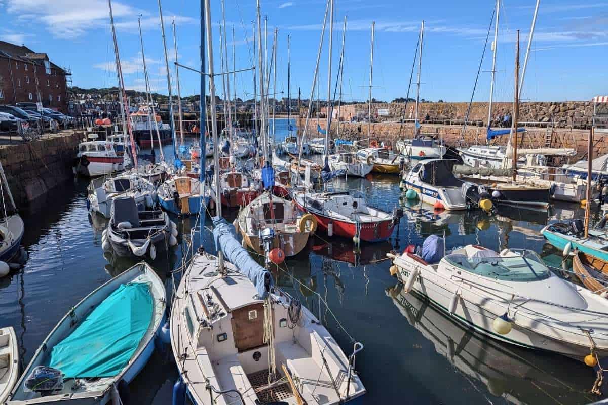 Colourful boats bob in the water in a small harbour on a sunny day. 