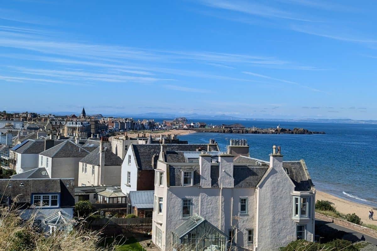 View of elegant whitewashed houses with large windows set behind a long sandy beach. North Berwick in the sunshine. 
