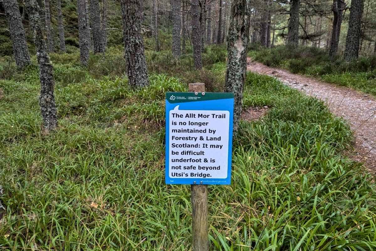I Did a Cairngorm Reindeer Hill Trip: Here's What It's Like 10 A forest path with a sign next to it saying that the Allt Mor Trail is no longer maintained by Forestry & Land Scotland.