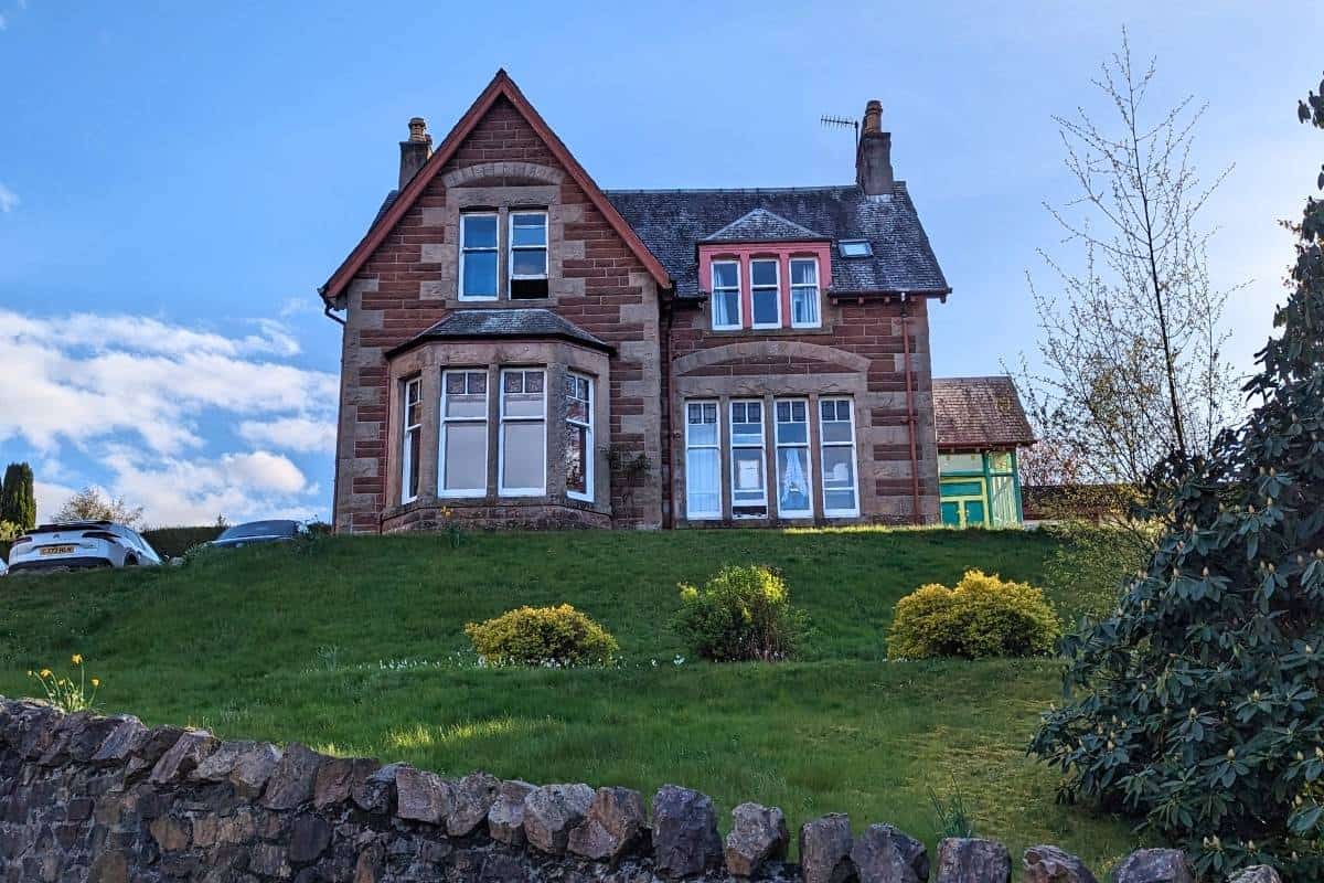 Where to Stay in Scotland Without a Car: Best Areas + Hotels 12 View of a Victorian building on top of a hill. Fort WIlliam Backpackers.