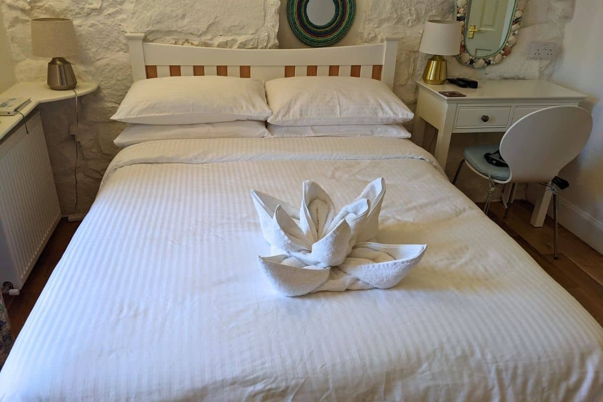Where to Stay in Scotland Without a Car: Best Areas + Hotels 20 A clean white bed with a towel on top in the shape of a flower. Harbour View B&B in Tobermory.
