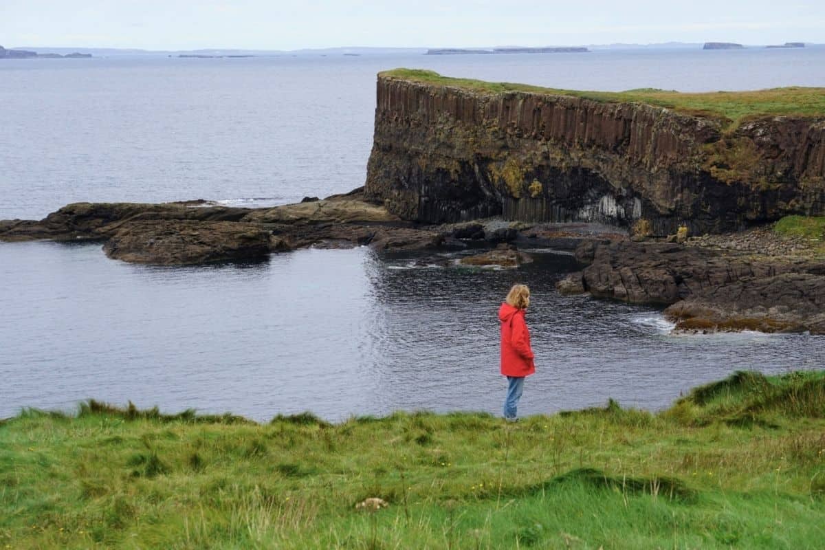 I Visited the Puffins of Lunga: Here’s What It’s Like 9 A woman wearing a red coat and blue jeans stands on the Isle of Staffa.